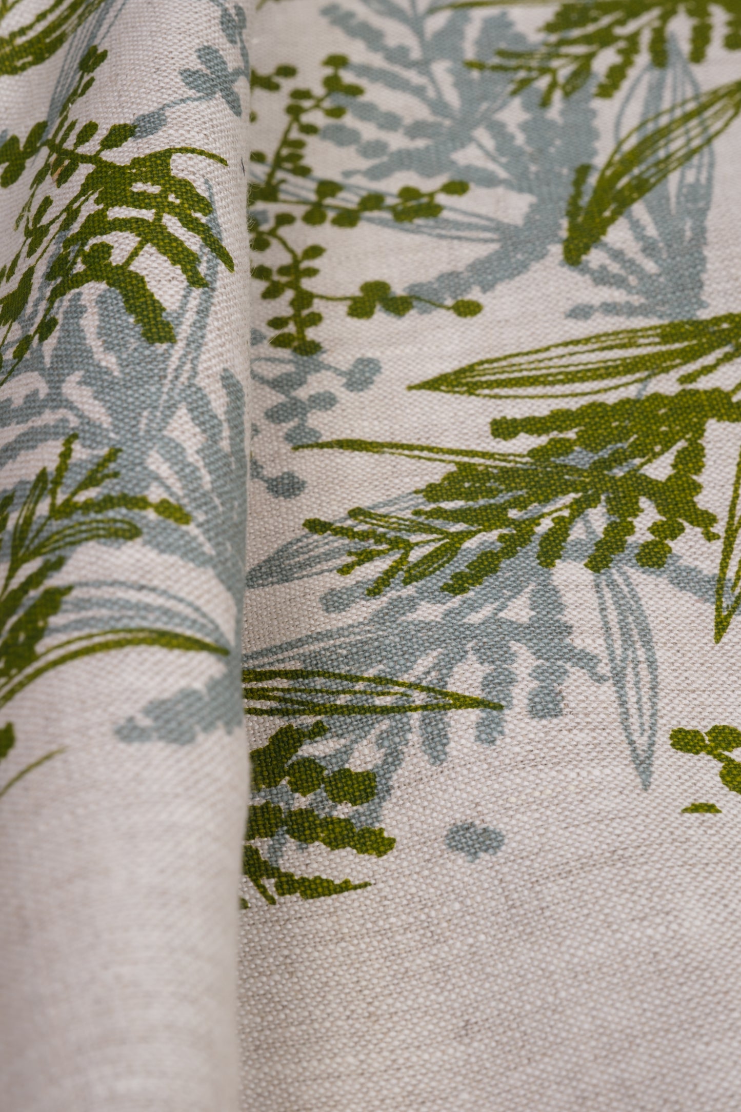 Screen printed linen fabric with a wattle print in storm and moss. Designed and printed by Femke Textiles. Base oatmeal linen.