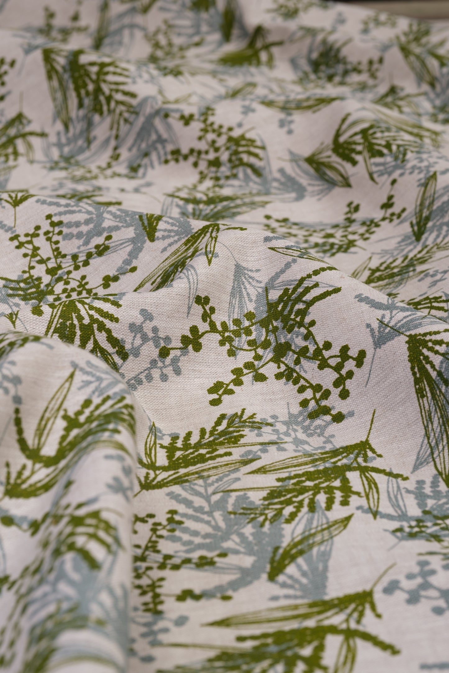 Screen printed linen fabric with a wattle print in storm and moss. Designed and printed by Femke Textiles. Base cloth oatmeal linen.
