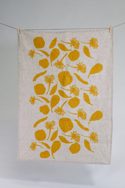 Linen tea towel screen printed with seedpod shapes in mustard. Printed and designed by Femke Textiles